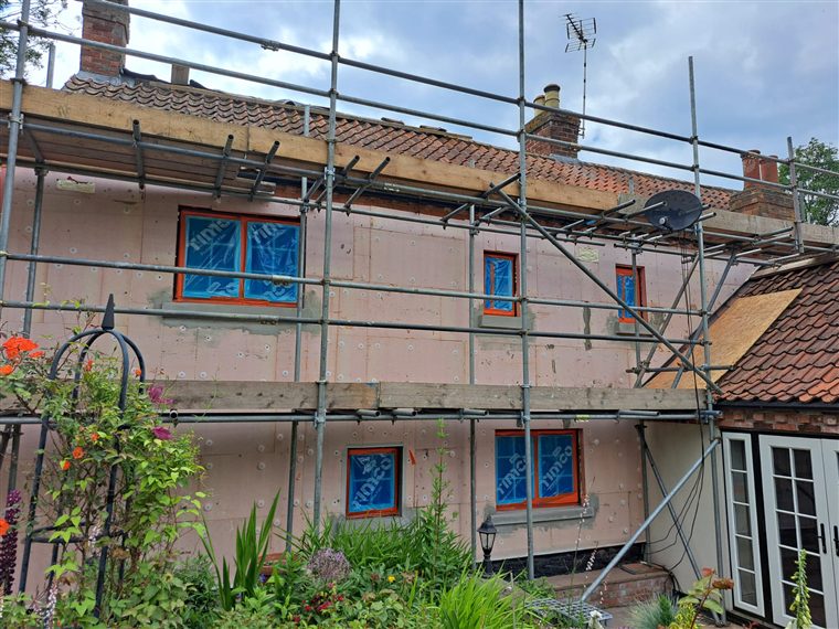 Insulation boards fixed across the outside walls of a house, ready for render