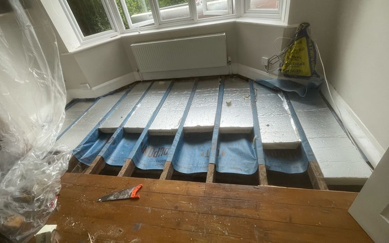 Insulation going in between the floor joists of a bay windowed room in Beeston